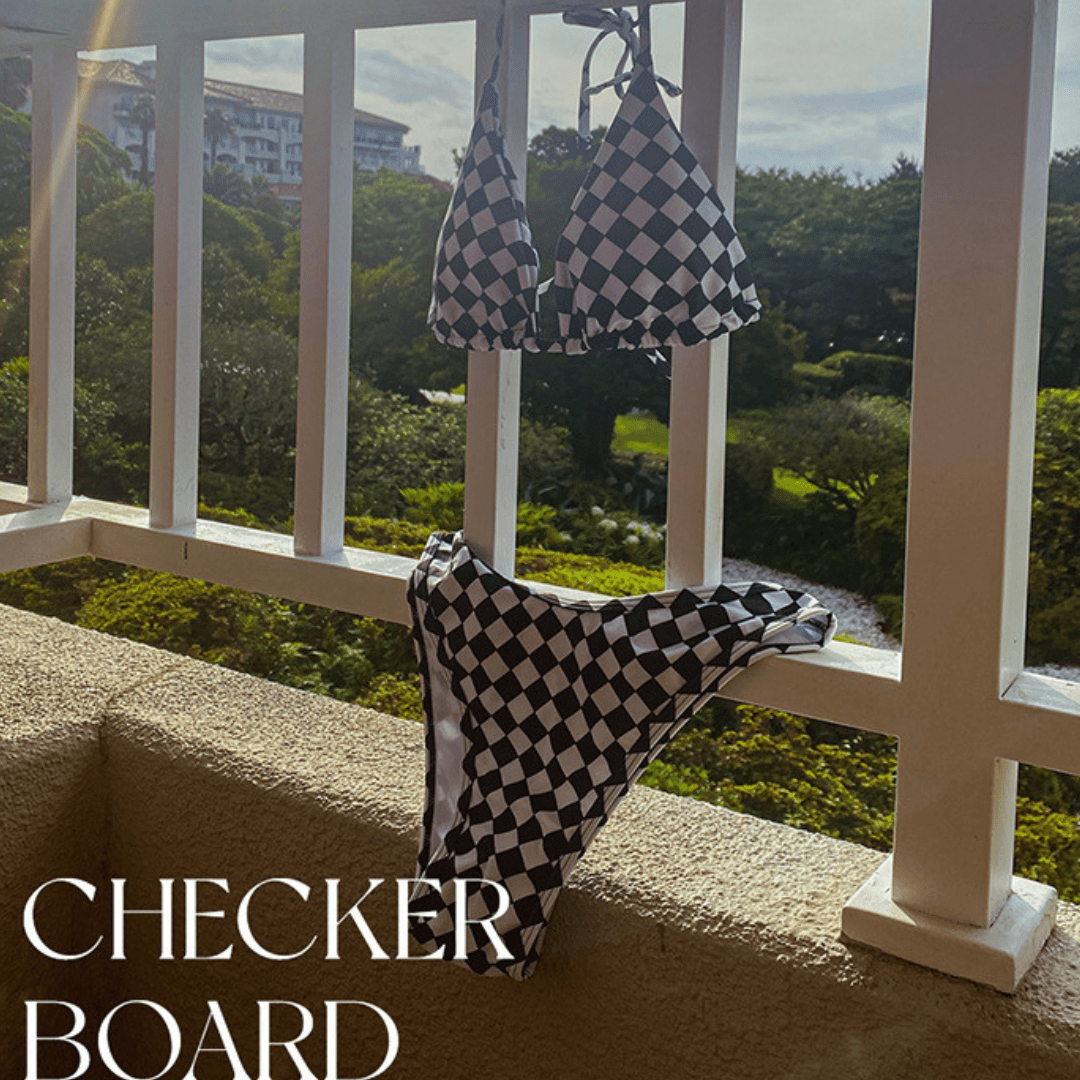 Checkered swimsuit and towel hanging on a balcony railing with a scenic view.