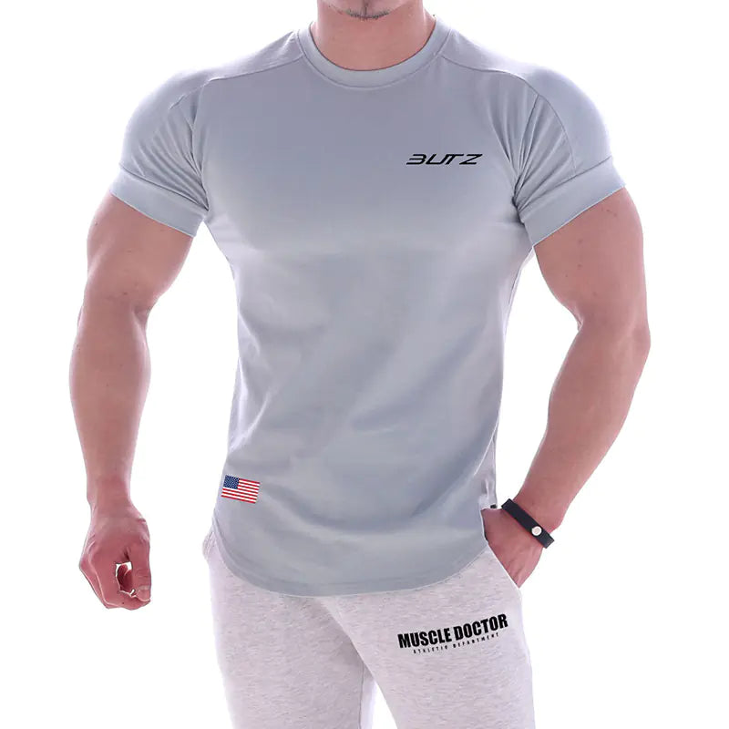 Person wearing a gray t-shirt with 'Butz' branding and gray pants with 'Muscle Doctor' branding on a white background.