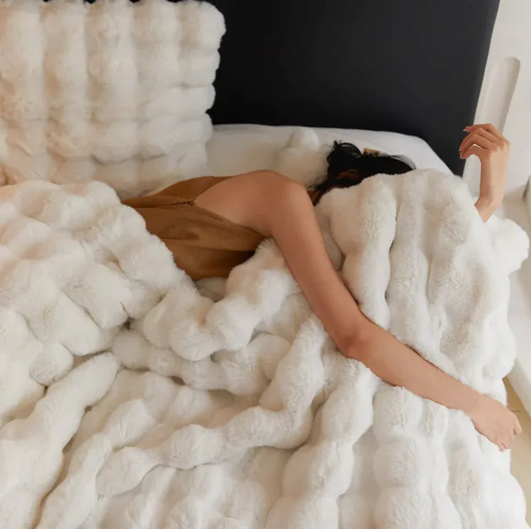 Person lying on a bed covered with a fluffy white blanket