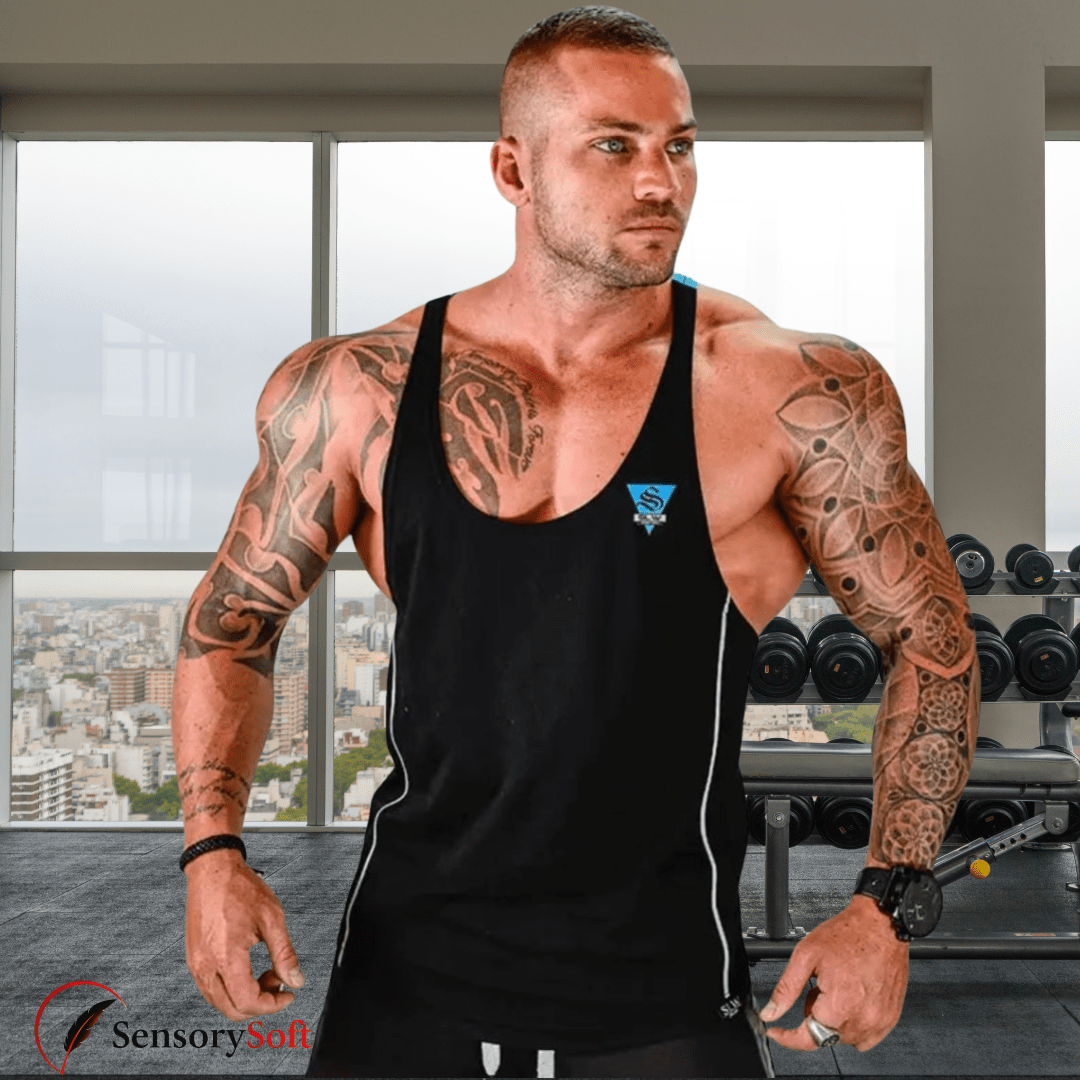 Muscular man with tattoos wearing a black tank top in a gym setting