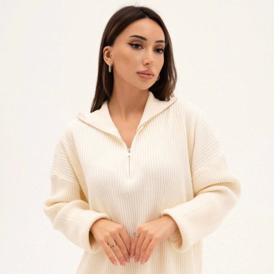 Woman wearing a cream-colored zip-up sweater against a white background