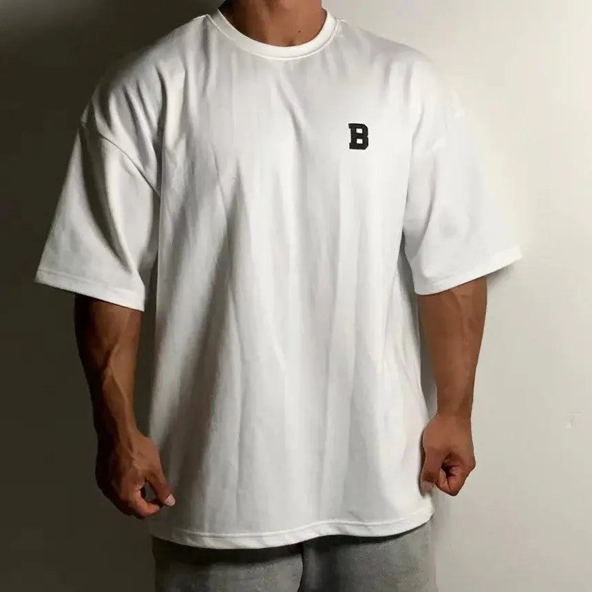 Person wearing a white t-shirt with a black letter 'B' logo on a plain background