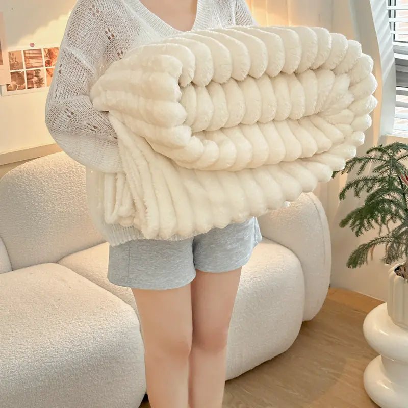 Person holding a large white knitted blanket in a cozy living room.