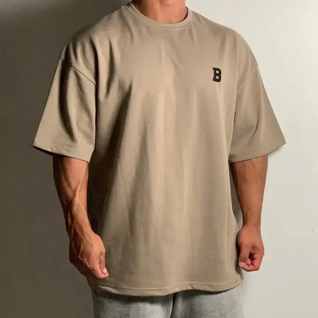 Person wearing a beige t-shirt with a logo on a plain background