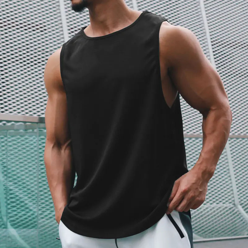 Man wearing a black tank top against a textured wall.