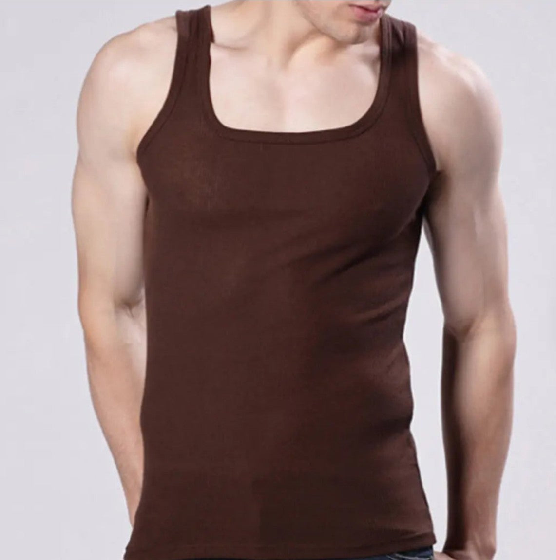 A man wearing a dark brown scoop-neck tank top against a light gray studio background.