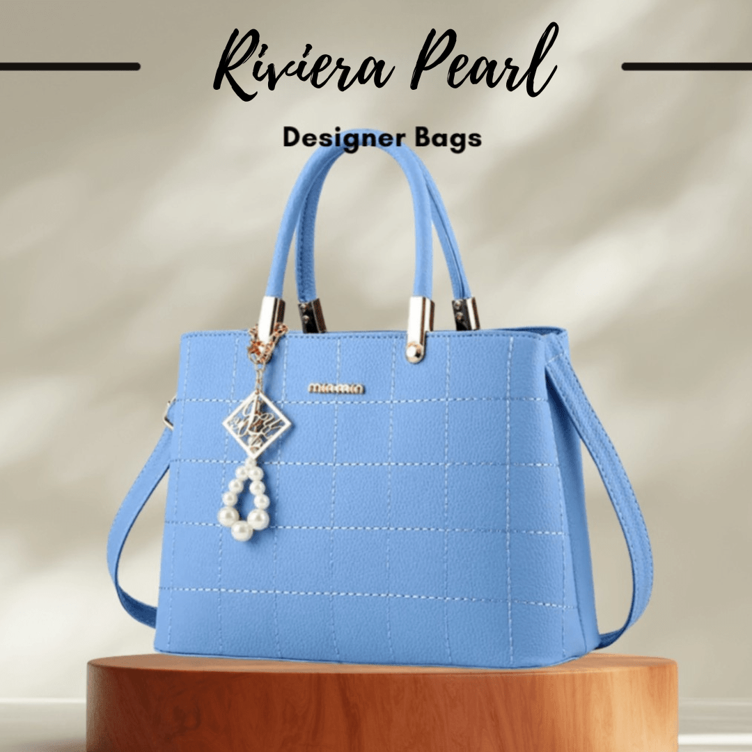 A light blue structured handbag with dual top handles, a shoulder strap, white pearl charm, and silver-tone hardware, displayed on a wooden pedestal with the text 'Riviera Pearl Designer Bags' above it.