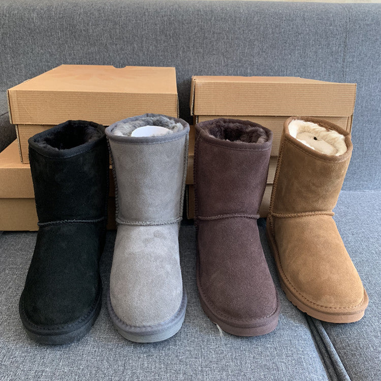Four pairs of colored boots with matching boxes on a gray surface.