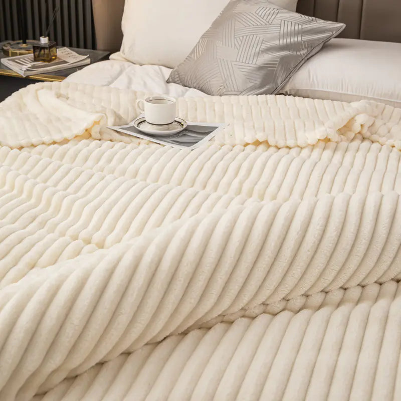 Beige comforter on a bed with a cup of coffee and a book on a nightstand.
