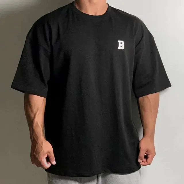 Person wearing a black t-shirt with a white logo on a plain background