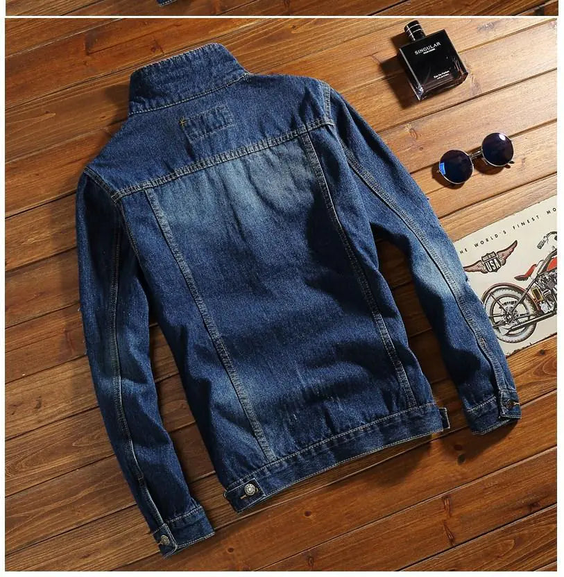 Blue denim jacket on a wooden surface with a bottle and sunglasses.